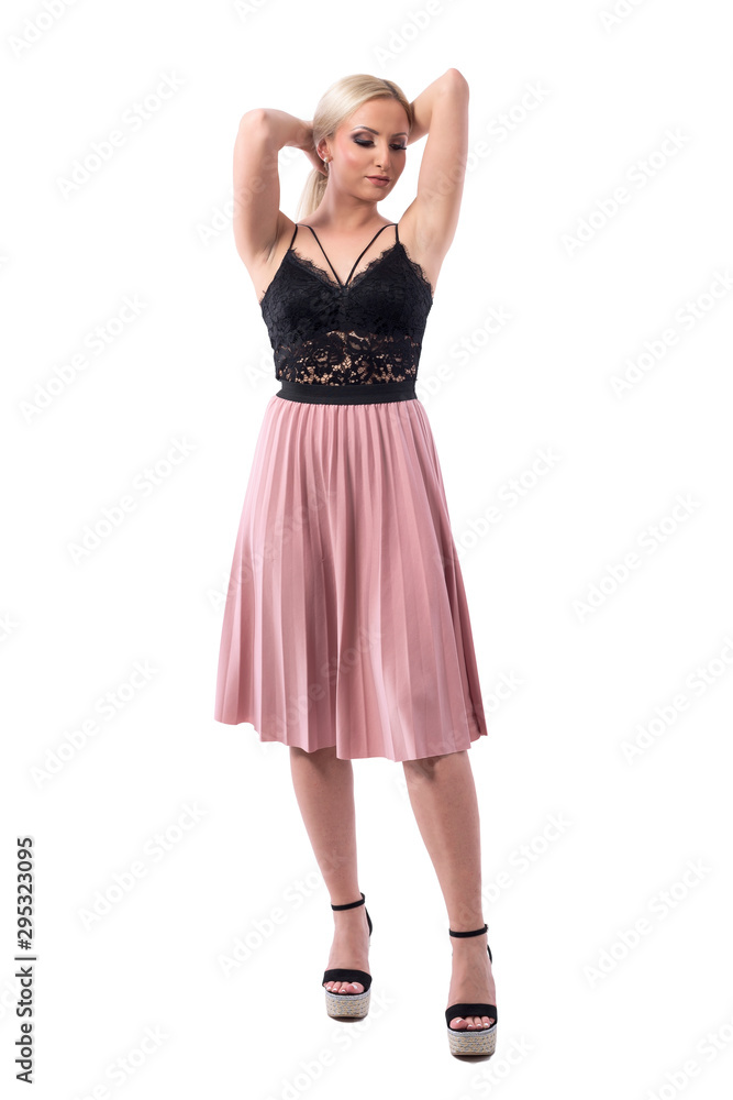 Classy young elegant blonde woman in evening wear with hands on hair looking down holding bun. Full body isolated on white background. Classy young elegant blonde woman in evening wear with hands on hair looking down holding bun. Full body isolated on white background.
