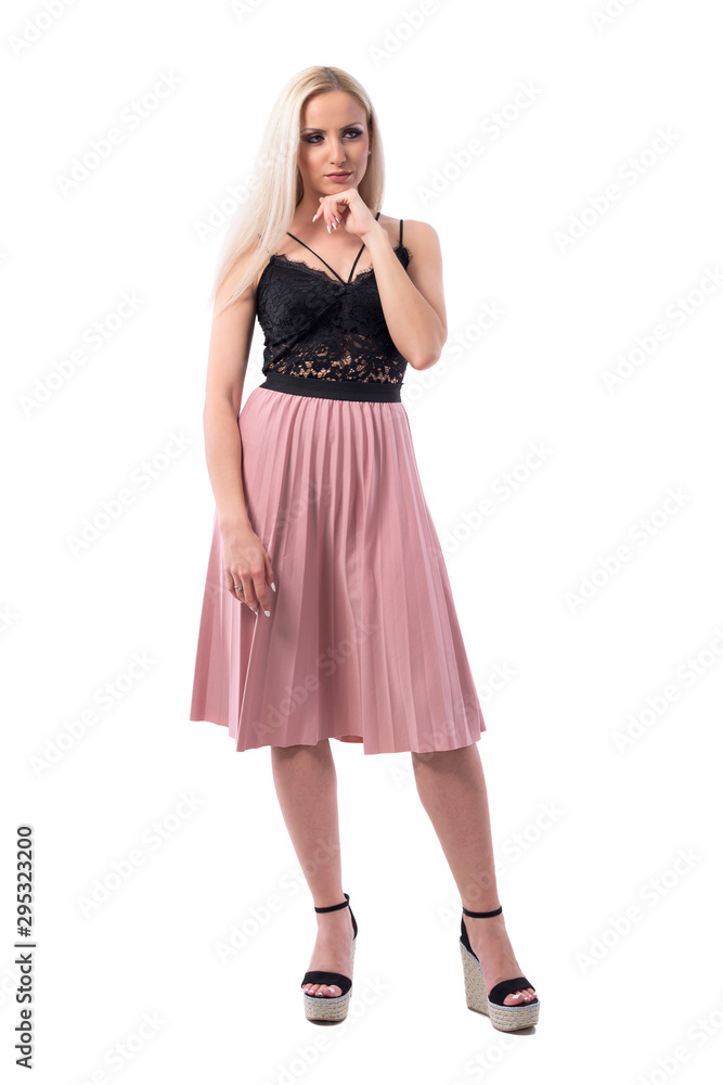 Skeptical distrustful young well dressed elegant woman with hand on chin looking away. Full body isolated on white background. 