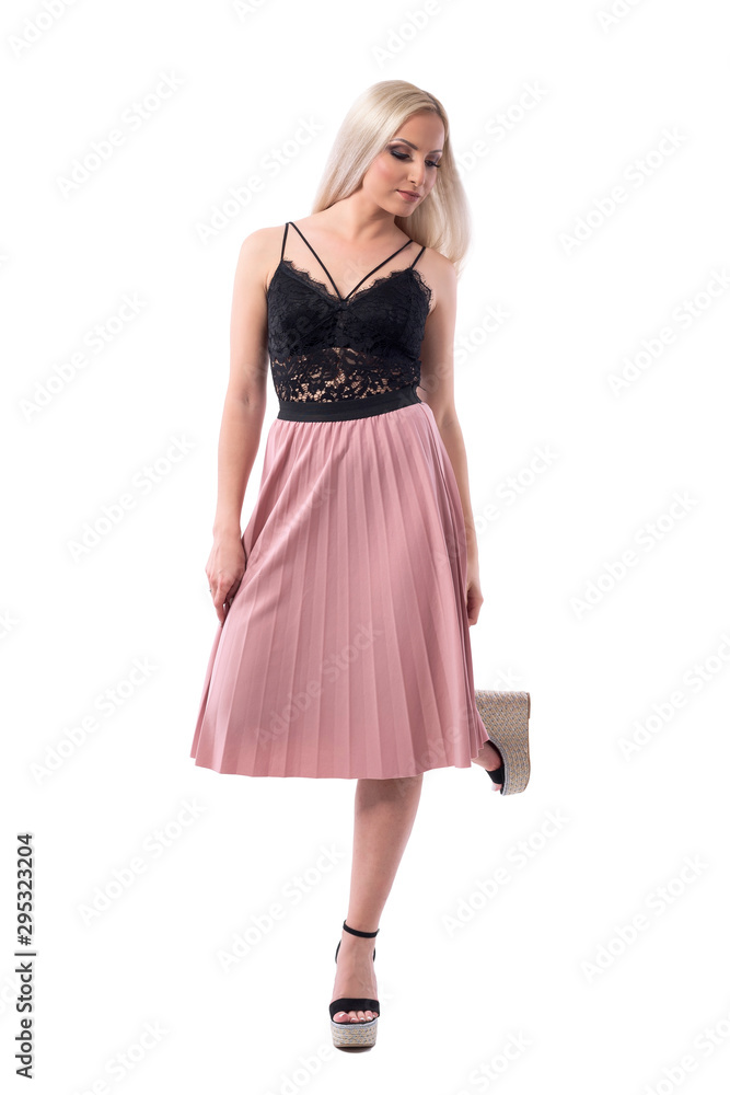 Elegant stylish well dressed woman in salmon skirt balancing on one leg looking down. Full body isolated on white background. Elegant stylish well dressed woman in salmon skirt balancing on one leg looking down. Full body isolated on white background.