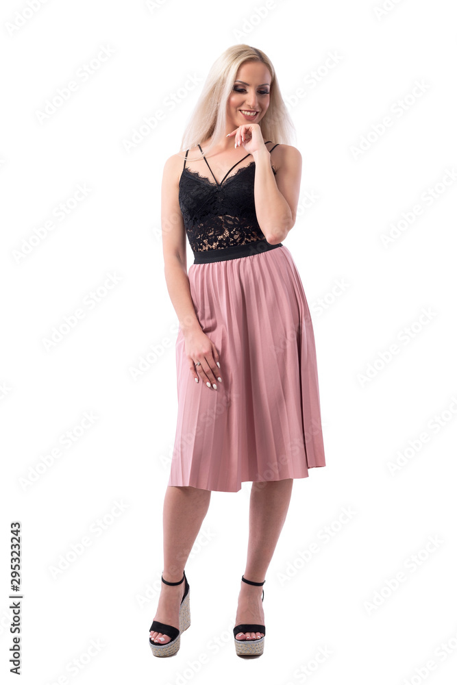 Beautiful blonde young modern woman in classy clothes thinking and smiling looking down with hand on chin. Full body isolated on white background. 