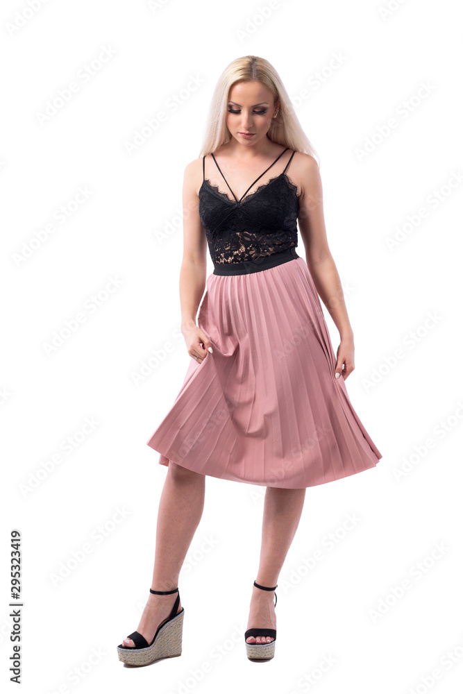 Elegant feminine blonde woman in evening wear lifting skirt looking down at feet. Full body isolated on white background. Elegant feminine blonde woman in evening wear lifting skirt looking down at feet. Full body isolated on white background.