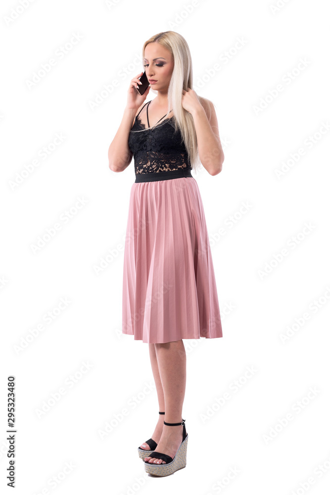 Worried displeased young well dressed woman in skirt looking down and talking on the cellphone. Full body isolated on white background. Worried displeased young well dressed woman in skirt looking down and talking on the cellphone. Full body isolated on white background.