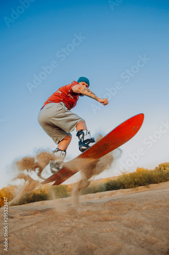 Photography Tourist Sandboarding In the Desert Man jumps in and does the trick