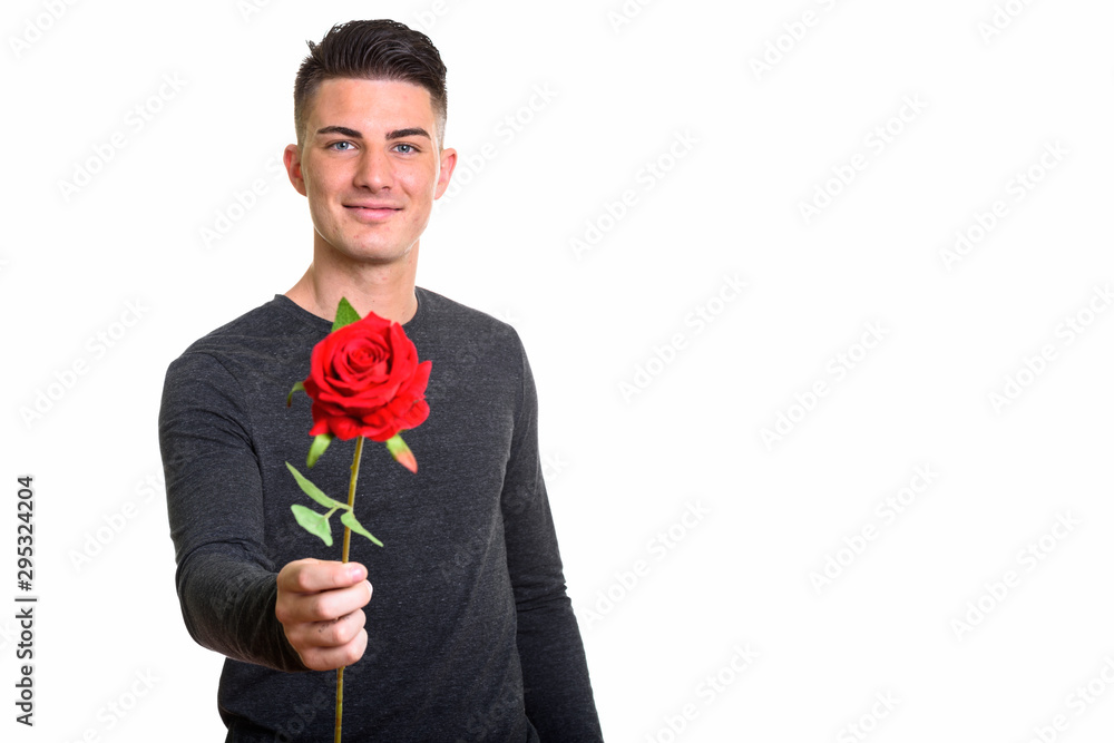 Studio shot of happy handsome man smiling while giving red rose Studio shot of happy handsome man smiling while giving red rose