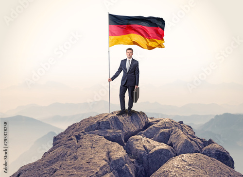 Successful businessman on the top of a mountain holding victory flag