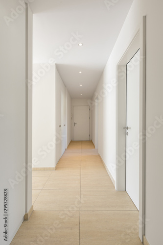 Corridor with travertine floor  white walls and built-in wardrobes