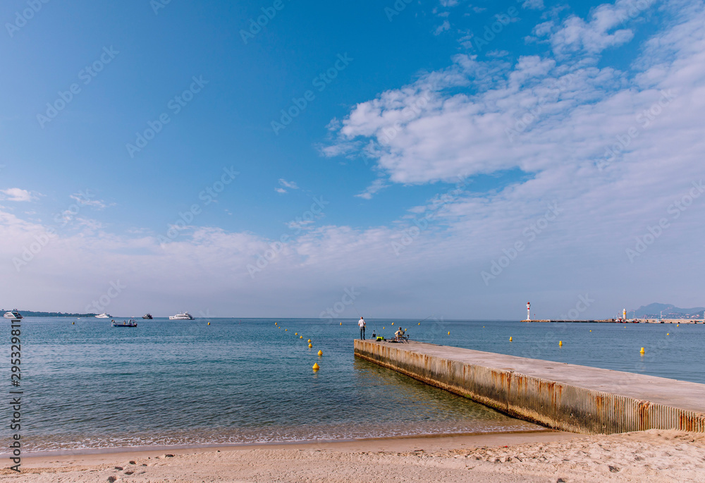 Obraz premium Men fishing a quiet beach close to the harbour of Cannes at the French Riviera, the Cote d'Azur, France