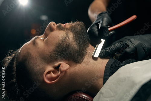 Close up of barber's hands shaving beard for client