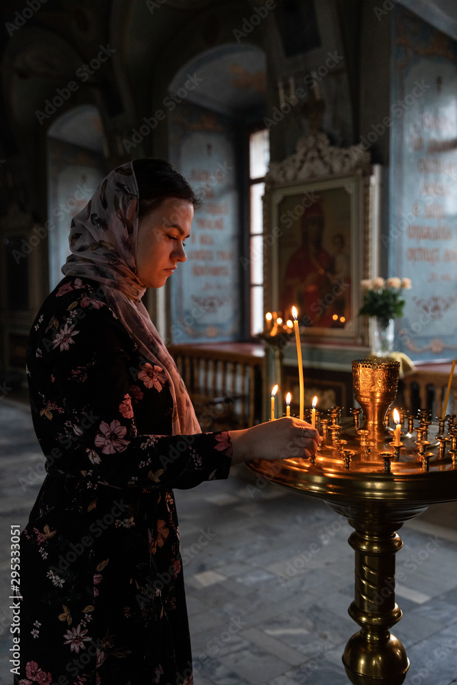 young godmother puts a candle in the Church young godmother puts a candle in the Church