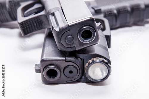 Two black semi automatic 9mm pistols, one with a flashlight attached below the muzzle on a white background