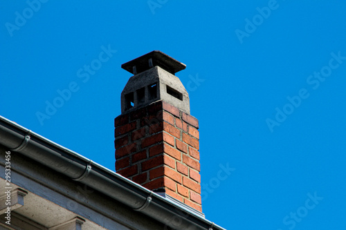 Fototapet Tiled roof with an old chimney against a blue sky