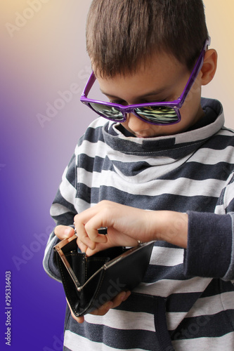 boy in dark sunglasses, in a striped sweater, takes out paper notes of the EU banknotes, copy space, purple background, close-up © kittyfly