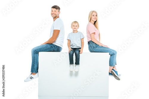 happy parents and son sitting on cube isolated on white