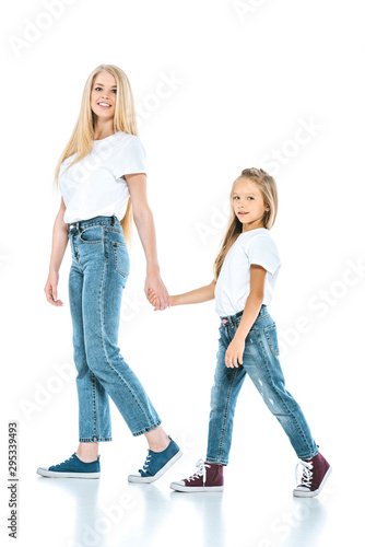 mother and daughter holding hands while walking on white