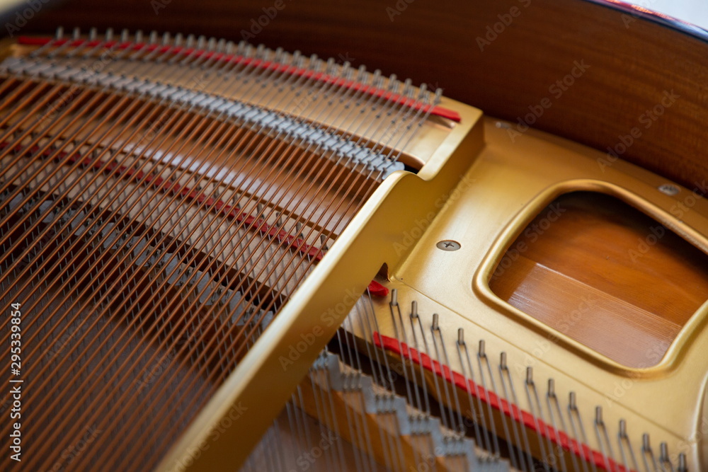 close up strings coil inside a gold wooden piano music instrument . close up strings coil inside a gold wooden piano music instrument .