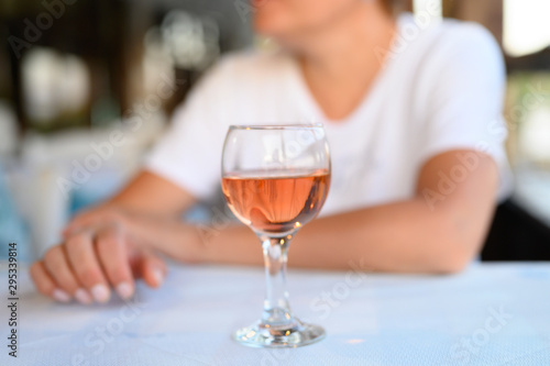 a glass of rose wine on the table in a restaurant on a blurred background of women's hands