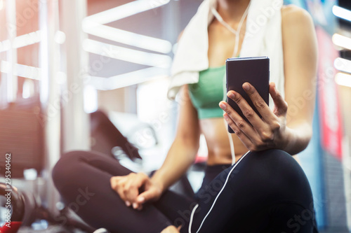 Closeup of sport woman using mobile after exercise at gym.