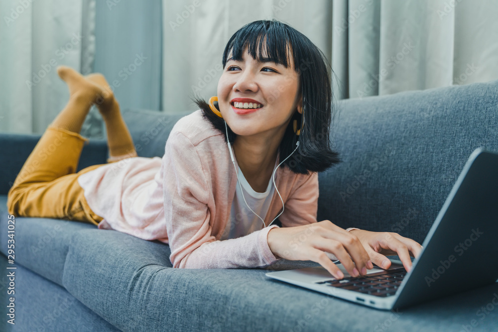 Young woman using laptop with smile on sofa at home. Young woman using laptop with smile on sofa at home.