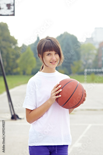 teenage girl holding basketball in school court sport