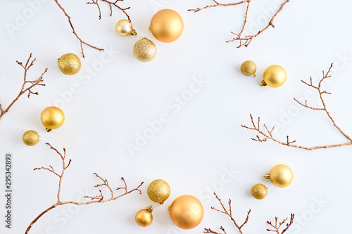 Flat lay frame with gold christmas balls and branches on a white background