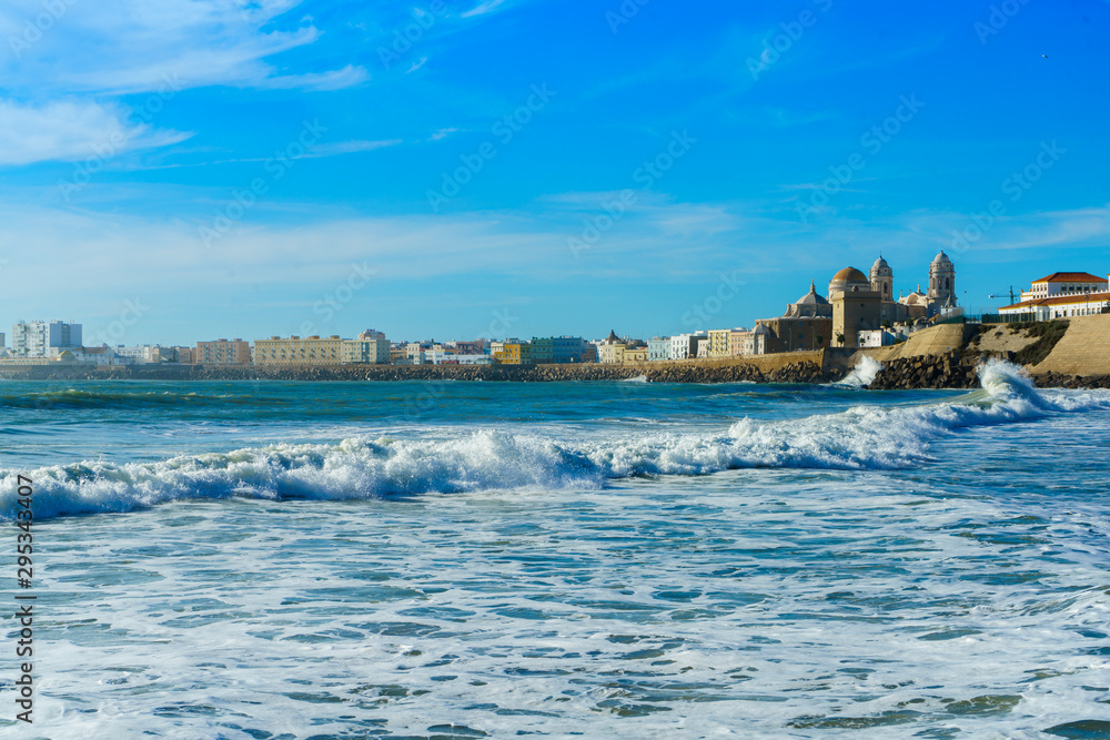 Foam sea waves in Cadiz, Spain, Andalusia. Old town view on the background