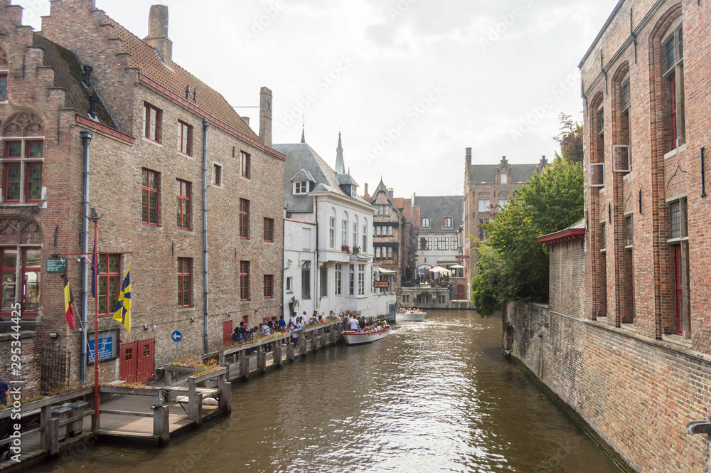 Bruges, Belgium. Medieval ancient houses made of old bricks at water channel with boats in old town. Picturesque landscape.