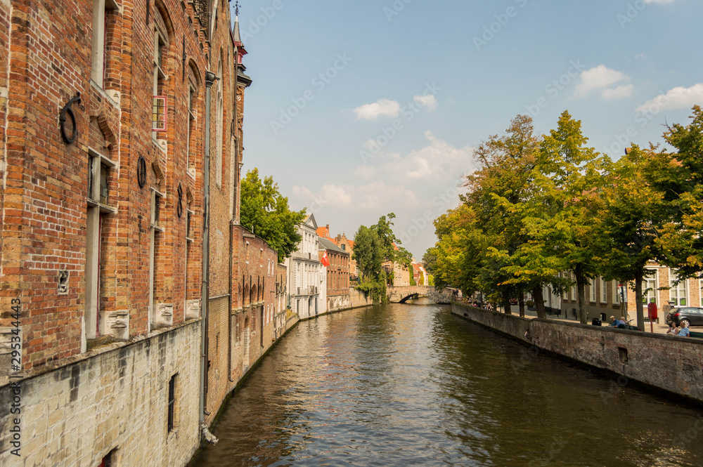 Obraz premium Bruges, Belgium. Medieval ancient houses made of old bricks at water channel with boats in old town. Picturesque landscape.