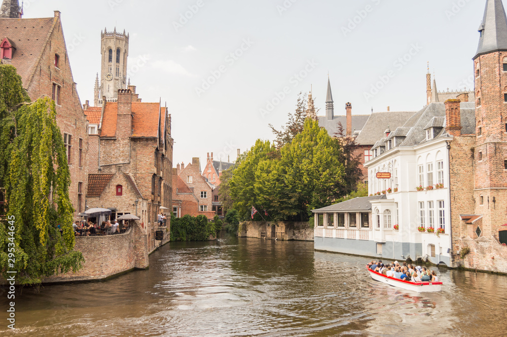 Bruges, Belgium. Medieval ancient houses made of old bricks at water channel with boats in old town. Picturesque landscape.