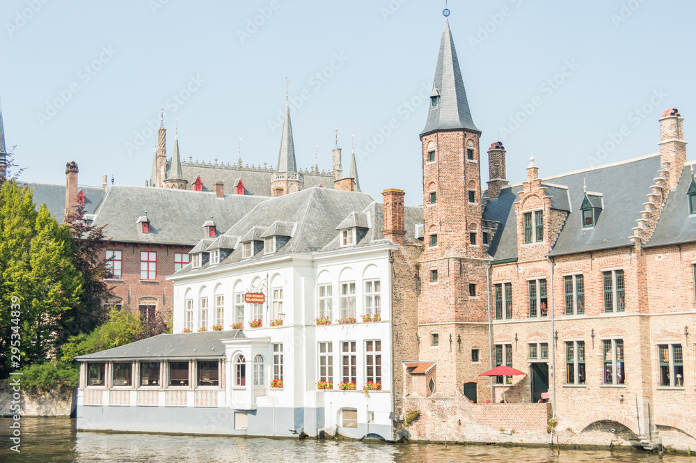 Fototapeta premium Bruges, Belgium. Medieval ancient houses made of old bricks at water channel with boats in old town. Picturesque landscape.
