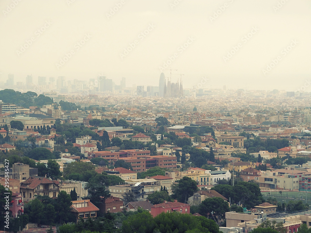 Barcelona panorama with the silhouette of the Sagrada Familia on the horizon on a cloudy foggy day. Beautiful urban landscape of an old tourist city, with blur effect