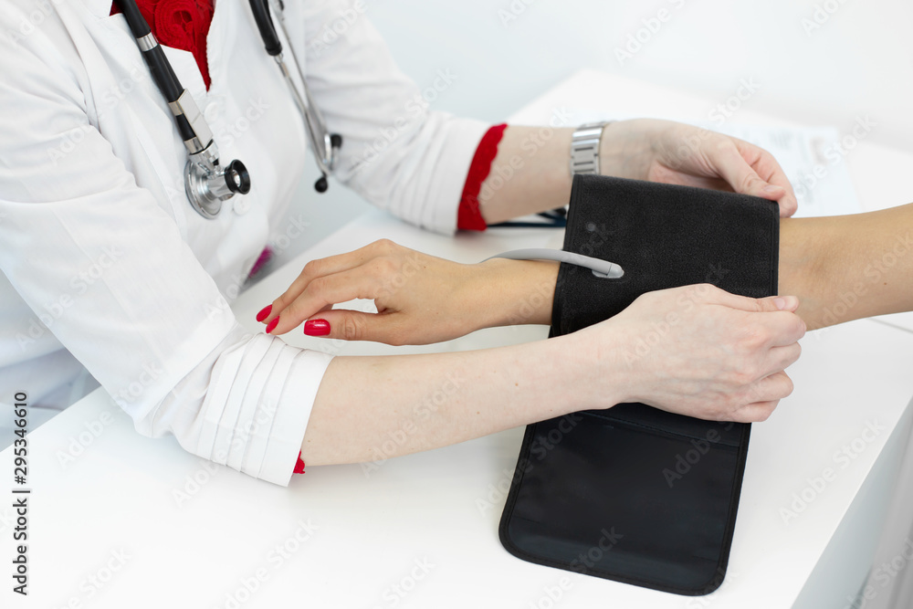Fototapeta premium Physiotherapist puts on a medical tonometer to measure pressure on the patients arm
