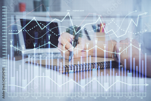 Financial graph displayed on woman's hand taking notes background. Concept of research. Double exposure © peshkova