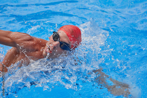 Swimmer in an outdoor pool, swimming in a crawl style, taking his head out of the water to breathe, side view and from above