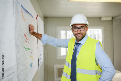 portrait of handsome foreman construction worker man on an industrial building industry construction site studying blueprint indoor