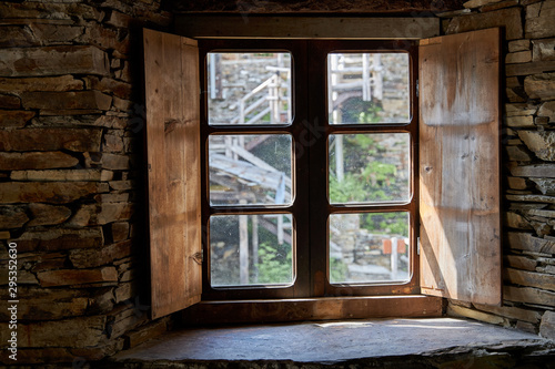 vista del exterior a trav  s de una ventana de madera y paredes de piedra 