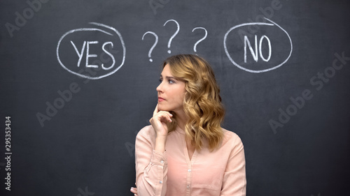 Puzzled woman choosing between yes no, stereotype of uncertain female thinking photo