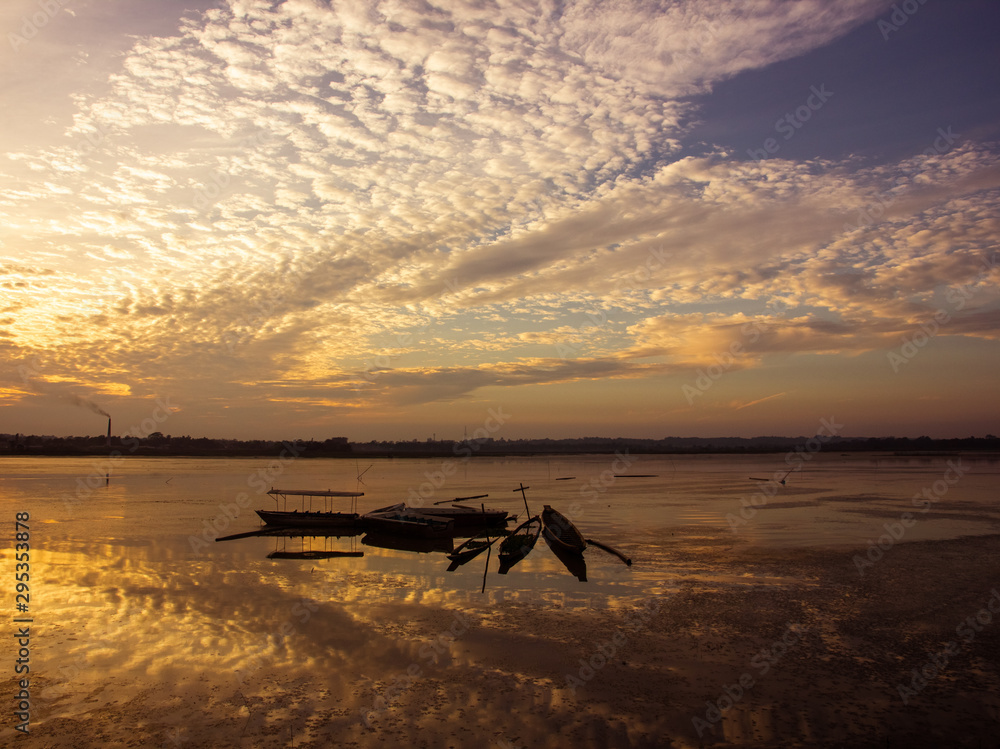 Obraz premium Fishing boats idle beneath cloudy skies on an evening on the Rudrasagar lake in Melaghar in the state of Tripura in Northeast India.