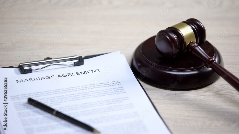 Marriage agreement on table, gavel lying on sound block, marital contract