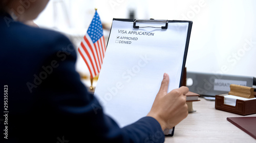 Immigration officer approving visa application, american flag on table, tourism