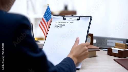 Female immigration inspector denying visa application, american flag on table photo