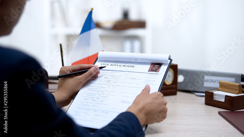 фотографія Embassy employee checking visa application office, french flag, migration