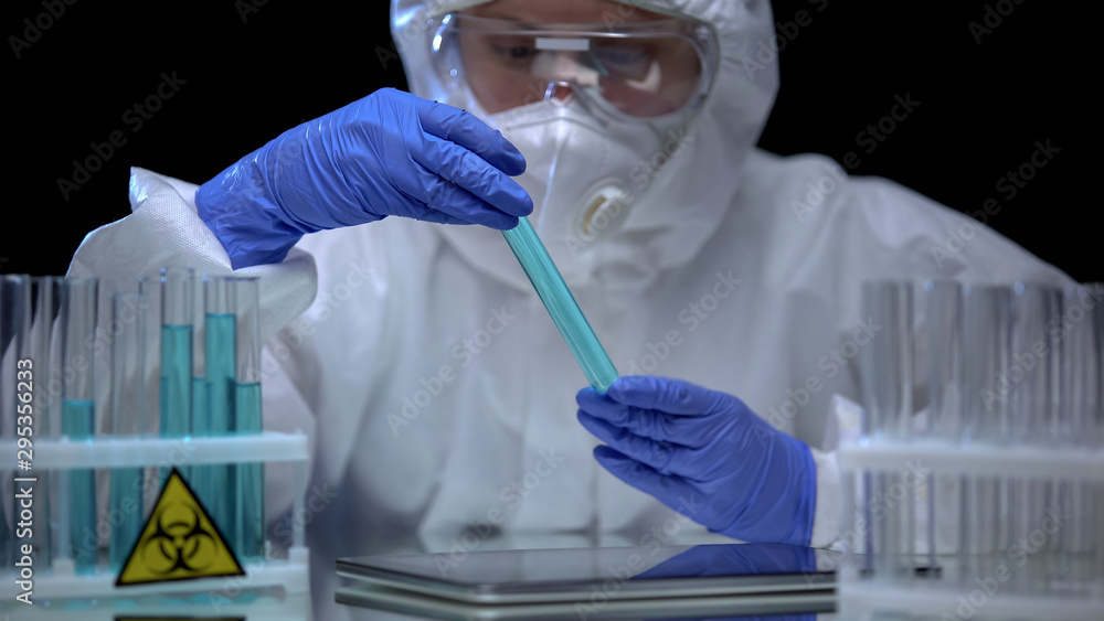 Female lab worker examining biohazard fluids in tubes, dangerous work ...