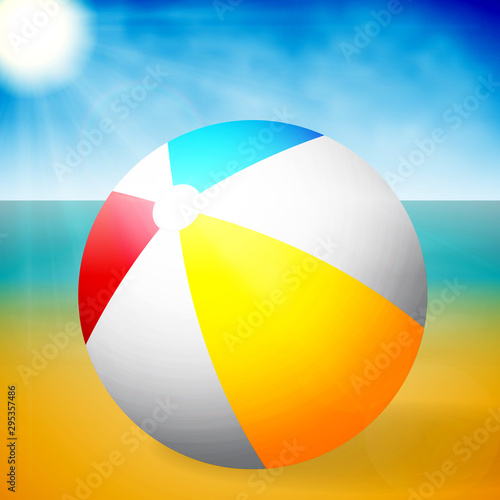 Summer colored rubber inflatable beach ball on abstract beach background.