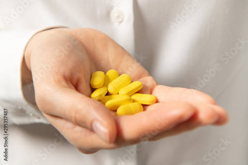 Woman offering a handful of yellow pills