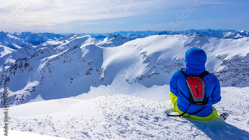 Skiing young man sitting on the snow in Mölltaler Gletscher, Austria, enjoying the view. Lots of snow in the mountains. Endless Alps chain. Winter wonderland, paradise. Calmness and happiness.