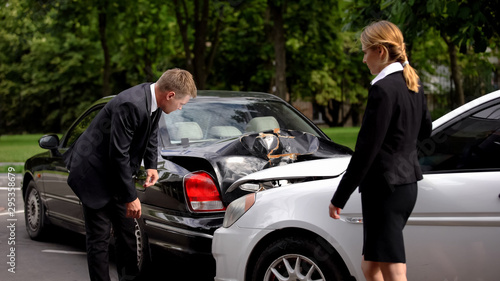 Male and female drivers examining car damage after accident, road conflict © motortion