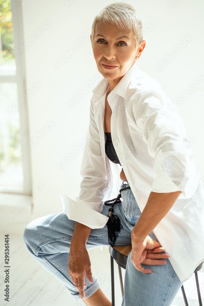 Cute blonde sitting on the chair and looking aside at wall Cute blonde sitting on the chair and looking aside at wall