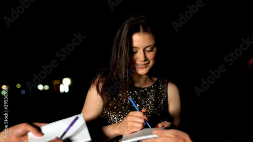 Fotografi Famous woman signing autographs in fans notebooks at evening party, stars life