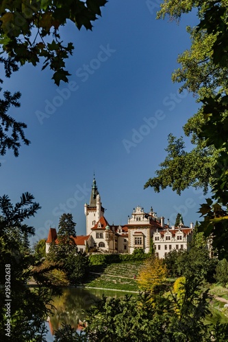 Pruhonice, Czech Republic - October 7 2019: Scenic view of famous romantic castle standing on hill surrounded with green trees. Sunny autumn day with bright blue sky. Vertical image.