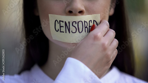 Woman taking off tape with censored word over mouth, democracy concept, freedom photo
